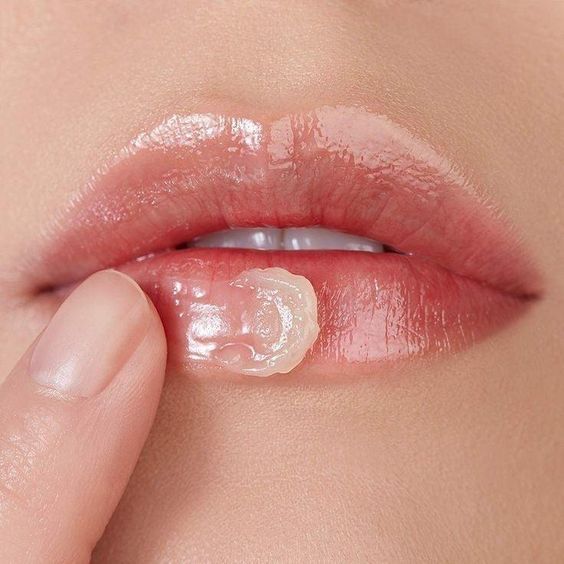 Clear balm being applied to lips with a fingertip