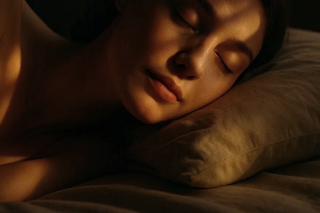 A person resting on a pillow in warm, low light